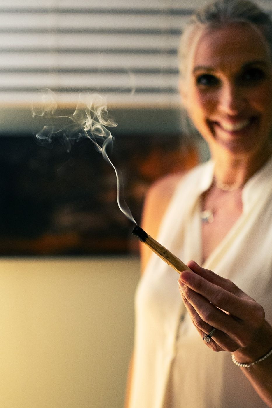Smoke curling up from a stick of palo santo in Tami Watson's hand