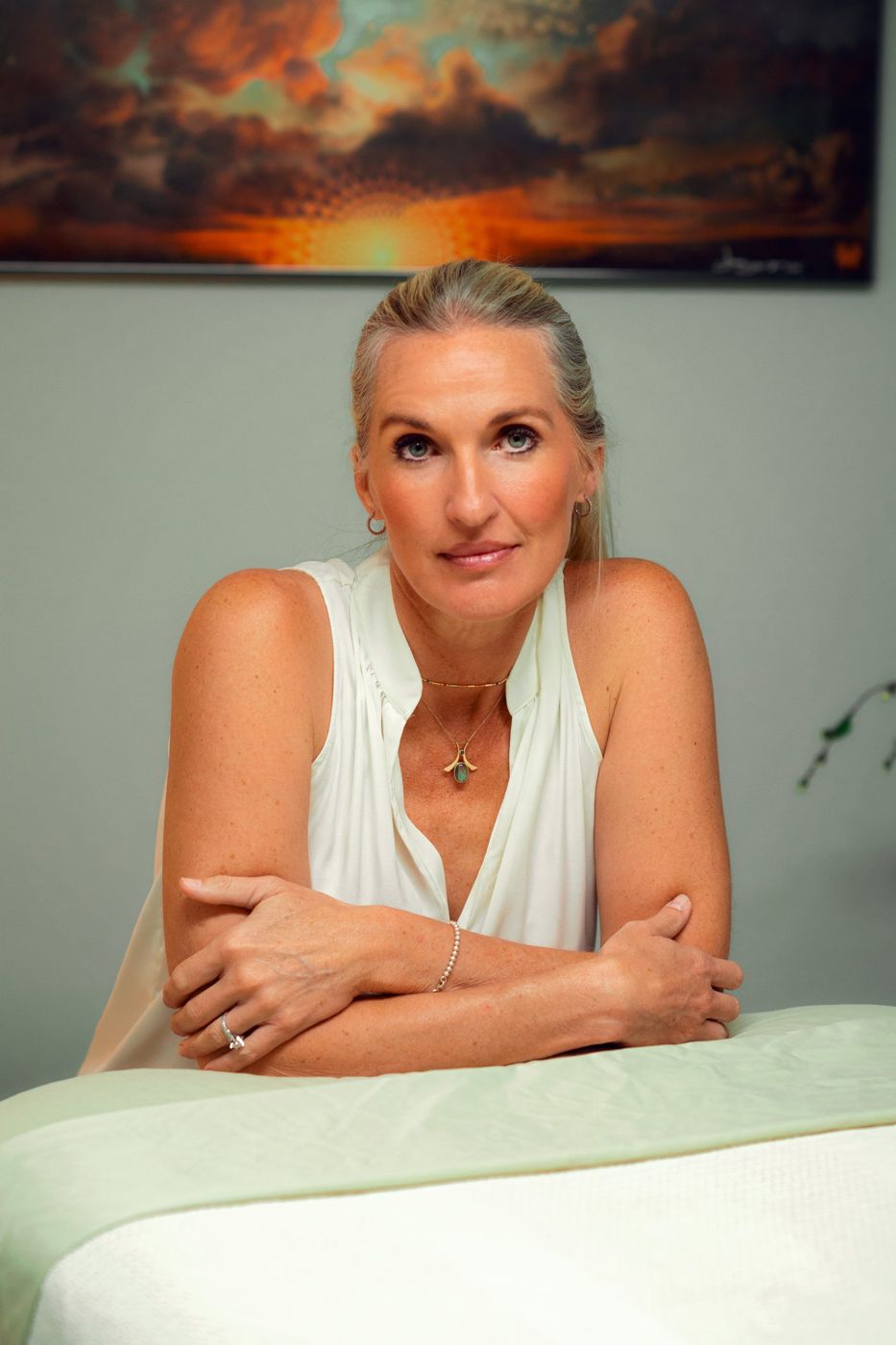 Tami Watson leaning on the massage table in her Millcreek studio